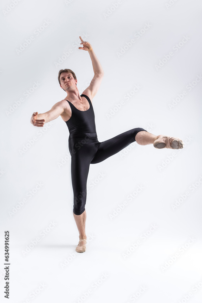 Sports Ideas. Athletic Caucasian Ballet Dancer Man Posing in Dancing Stretching Pose With Hands Lifted Up in While Standing on Feet in Black Tights On White.