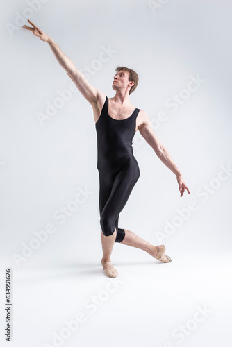 Sports Ideas. Young Athletic Caucasian Ballet Dancer Man Posing in Stretching Pose With Hands Aligned and Knees Bended in Black Tights On White.
