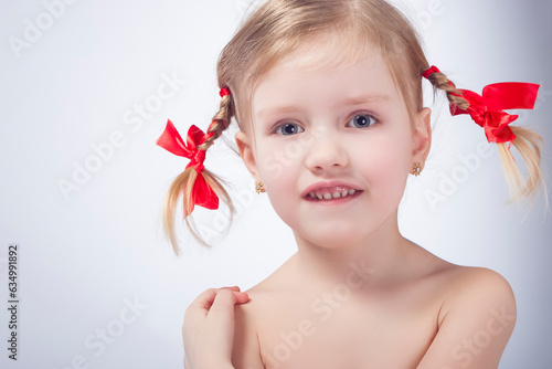 ittle Caucasian Girl Posing With Long Pigtails Against White Background. photo