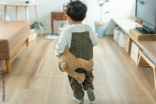 Obraz na plátně 秋の昼間の家の中でくまのぬいぐるみを抱えて走る日本人の子供の後ろ姿