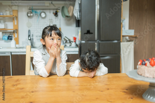 春の自宅の台所のテーブルでケーキを食べるのを我慢して待つアジア人の兄弟 photo