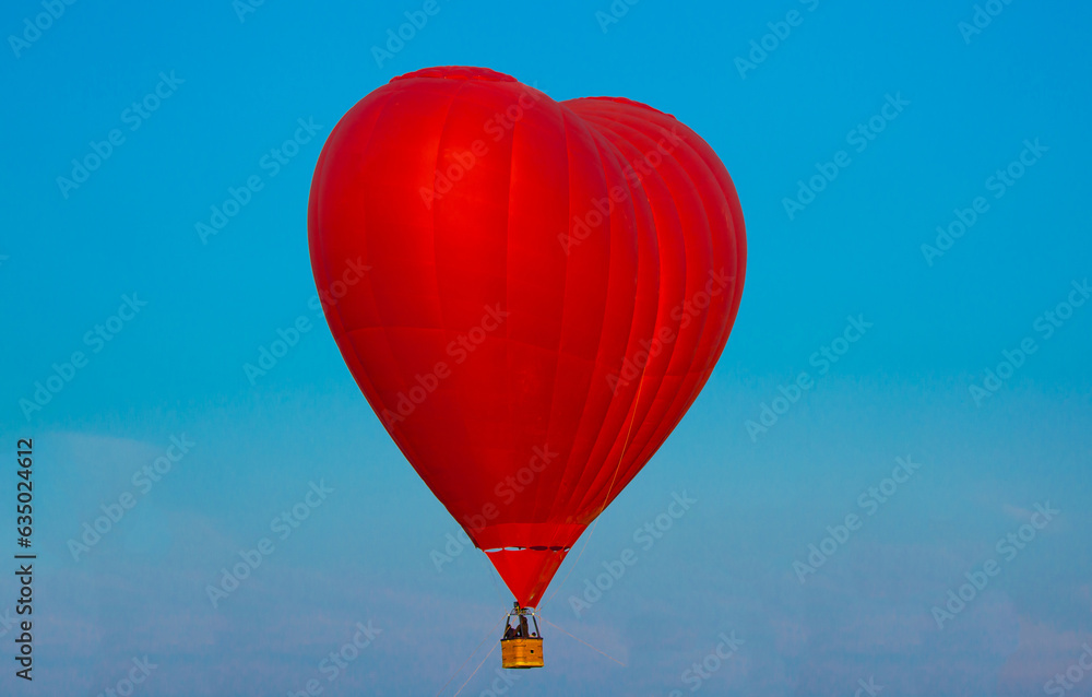 Love Balloon in the shape of a heart against the blue sky in flight, colorful cheerful entertaining mode of transport, flying in a balloon, concept of dreams and happiness. Red balloon aerostat. Love Balloon in the shape of a heart against the blue sky in flight, colorful cheerful entertaining mode of transport, flying in a balloon, concept of dreams and happiness. Red balloon aerostat.