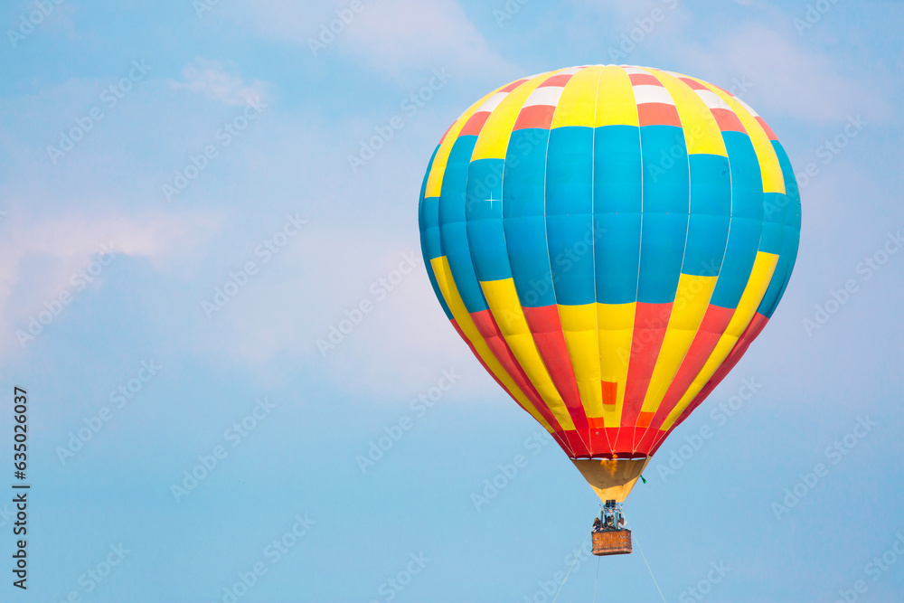 Fototapeta premium Hot air balloon against the blue sky in flight, colorful fun entertainment mode of transport. Hot air balloon flight, dream and happiness concept. Multi-colored balloon in flight.