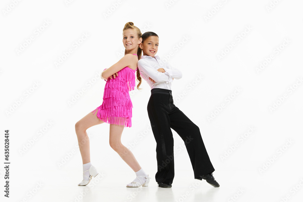 Beautiful kids, stylish boy and girl in stage costumes dancing retro style dance against white studio background. Concept of childhood, hobby, active lifestyle, performance, art, fashion