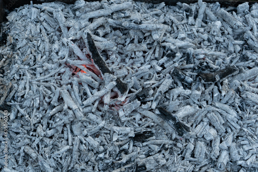 Grey coals texture background. Texture embers closeup. burning, decaying charcoal, coals, smoldering ashes with fire in steel barbeque brazier.BBQ barbecue season on open air