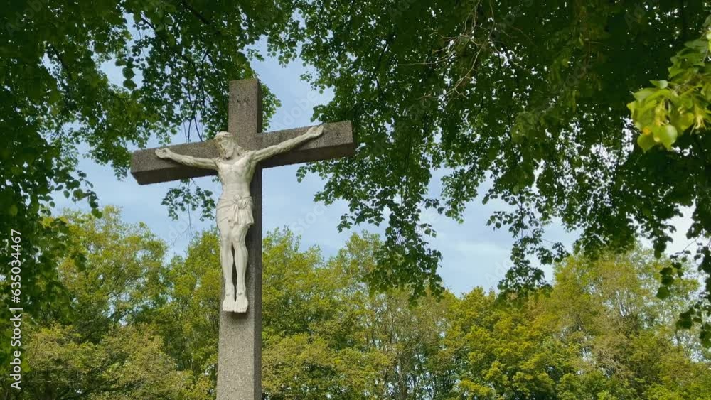 Jesus statue hangs on a concrete cross in Limburg during spring in a forest Jesus statue hangs on a concrete cross in Limburg during spring in a forest