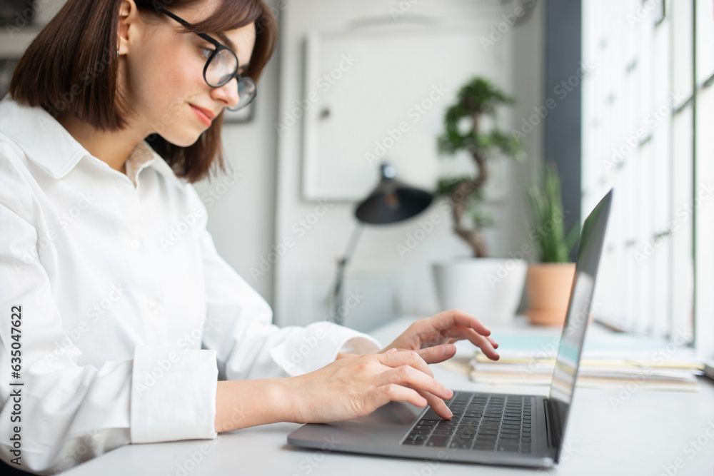 Young businesswoman in glasses working on computer, enjoying professional occupation, selective focus on hands Young businesswoman in glasses working on computer, enjoying professional occupation, selective focus on hands
