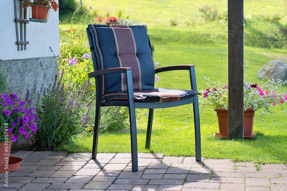 Modern chair in the beautiful summer terrace and blooming garden