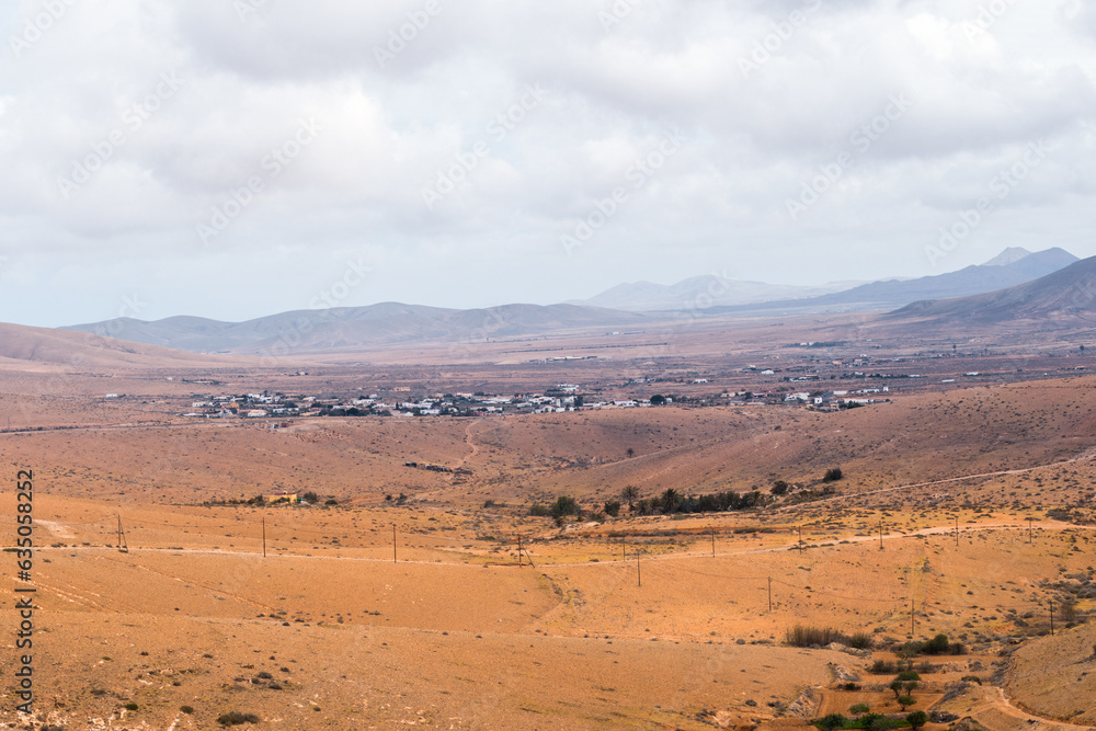 Fototapeta premium Desertic landscape of the interior of Fuerteventura island. Rocky hills with white sand. Sky with big white clouds. Sunny day Fuerteventura, Canary Islands, Spain.