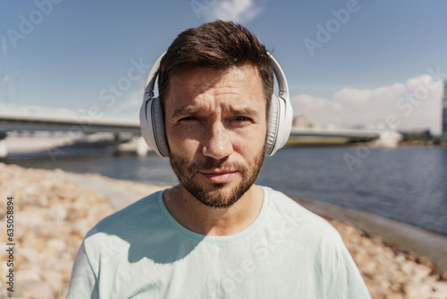 A portrait of a man listening to a music playlist with headphones  an athlete is close.