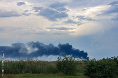 War in Ukraine 2023. Smoke in the sky, burning tank farm on city landscape. Environmental pollution and climate damage because of fuel fire