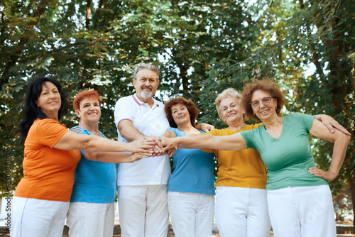 Team. Group of elderly people, pensioners, man and women standing in park, training together outdoors on war, summer day. Concept of sport and health, active lifestyle, age, wellness, body, care