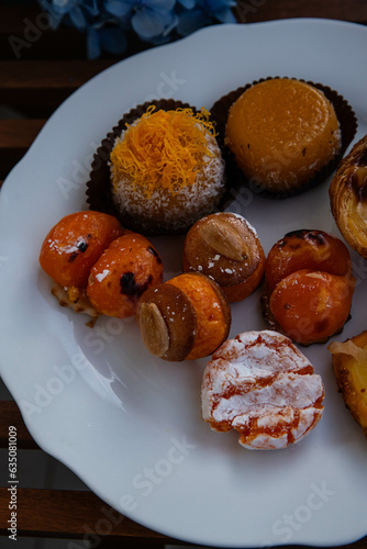 Mix of traditional Portuguese egg yolk sweets from Porto region on white plate with blue hydrangea on background.