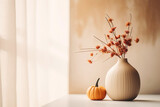 A vase with an arrangement of autumn flowers and leaves placed next to pumpkin decor. 