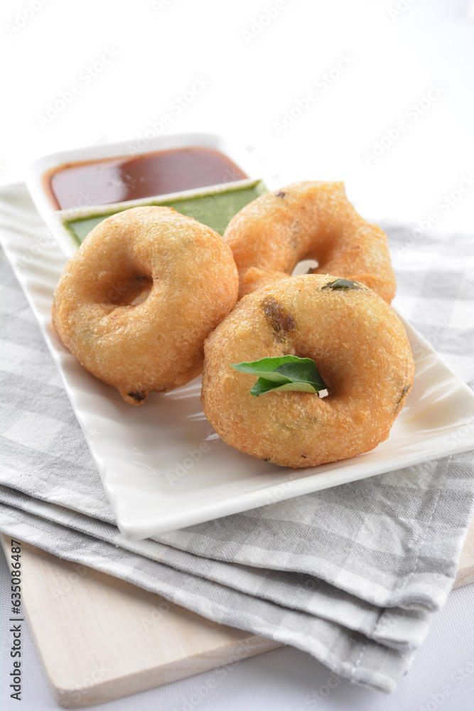 Indian vegetable deep fried mini donut bread in green yogurt and red