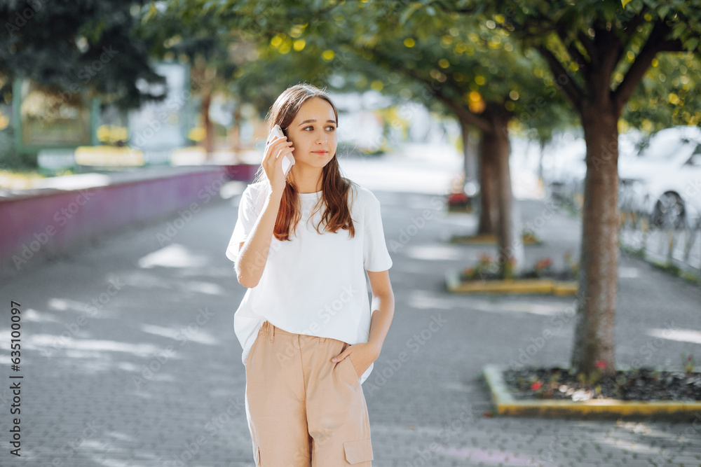 Front view of young happy teenage girl walking and using or talking on smart phone on city street Front view of young happy teenage girl walking and using or talking on smart phone on city street