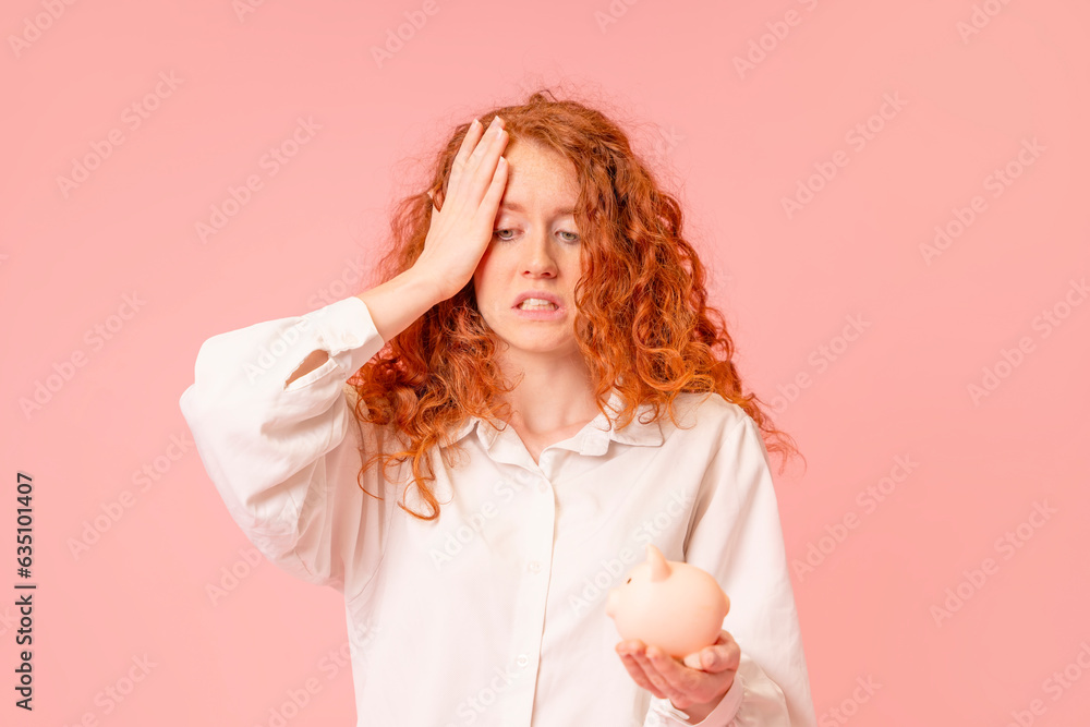 Unhappy woman in white shirt discovering empty piggy bank without savings. Investment, saving money, currency, deposit. Indoor studio shot isolated on pink background. Unhappy woman in white shirt discovering empty piggy bank without savings. Investment, saving money, currency, deposit. Indoor studio shot isolated on pink background.