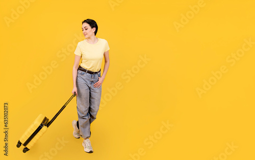joyful woman in blue t-shirt with yellow suitcase and passport on yellow background. Travel enjoy concept