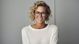 Young adult stylish confident attractive smiling blonde European business woman, beautiful lady pretty model with curly blond hair wearing glasses looking at camera, close up face portrait indoors.
