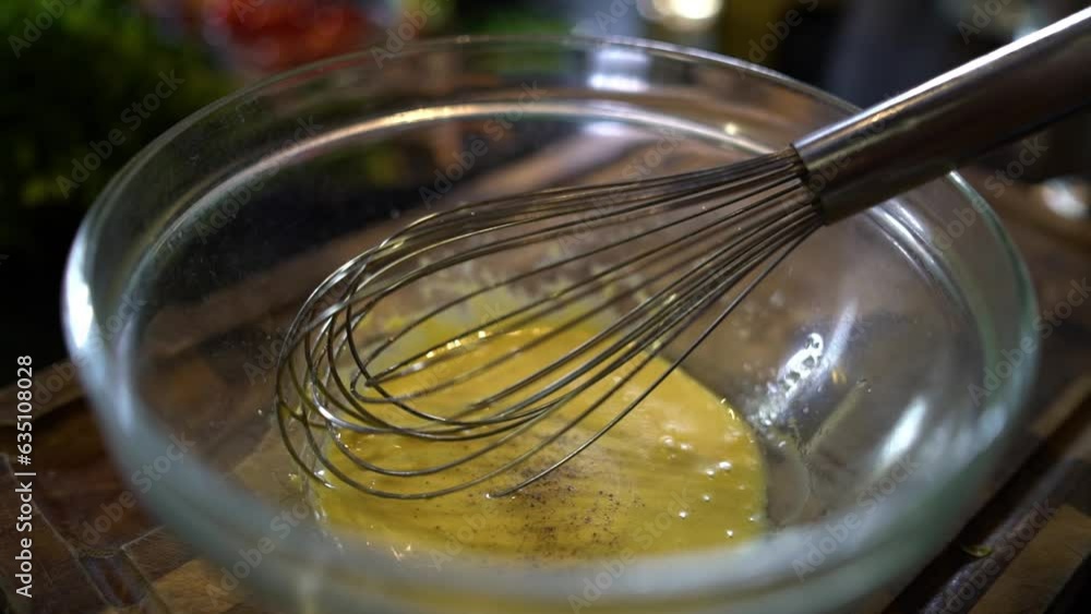 Black pepper being added to mixing bowl with whisk Black pepper being added to mixing bowl with whisk