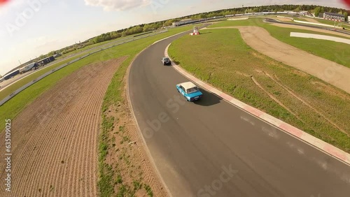 aerial filming of a circuit race on an asphalt circuit, fpv drone, racing cars go fast, time trials, sharp turns