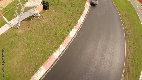 aerial filming of a circuit race on an asphalt circuit, fpv drone, racing cars go fast, time trials, sharp turns