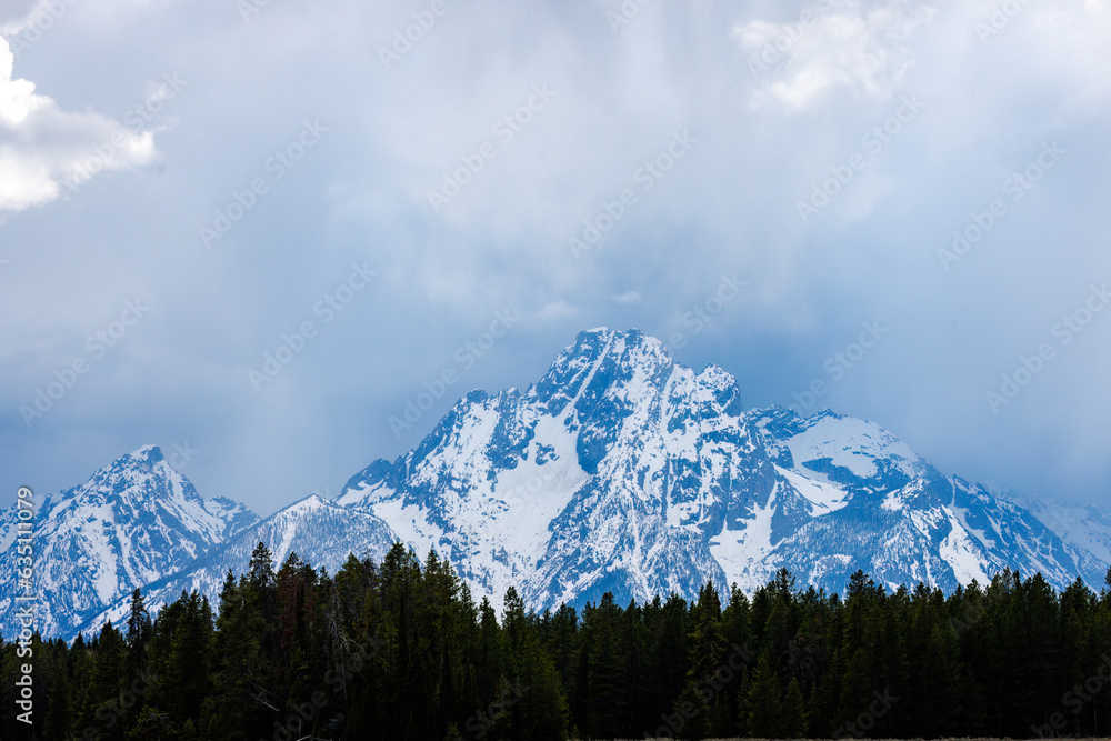 View of snow covered Mount Moran with clouds in Grand Teton National Park, Wyoming during spring. 
