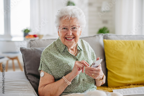 Diabetic senior patient using continuous glucose monitor to check blood sugar level at home.