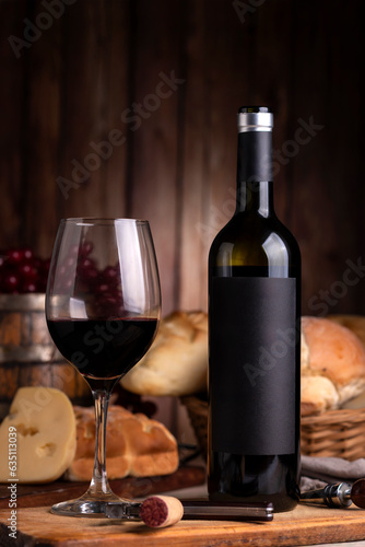 glass of red wine with bottle on table with homemade bread cheese wooden barrel with wooden boards