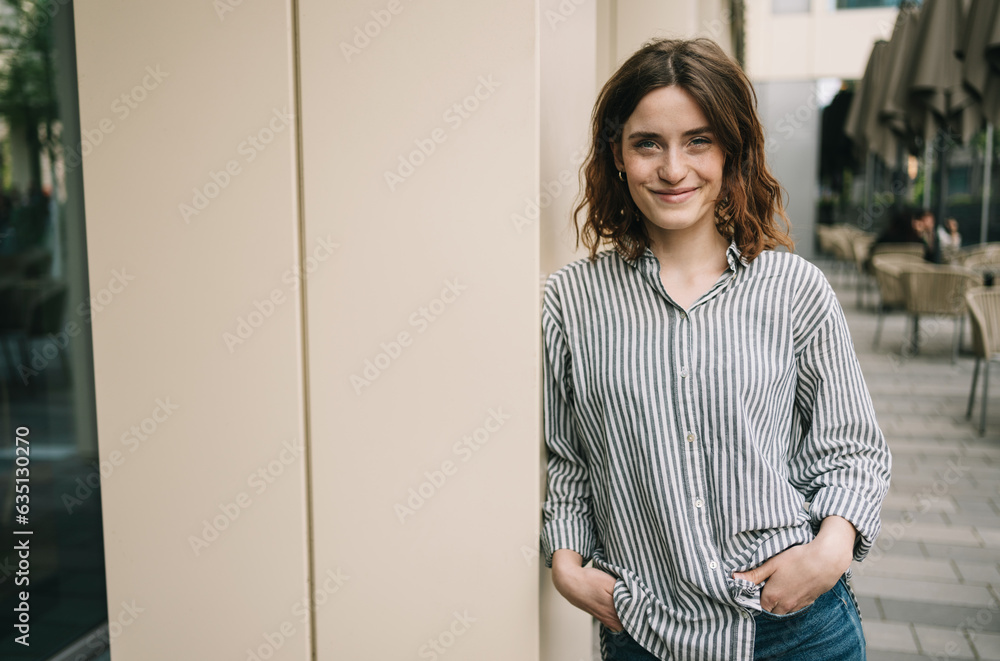Young Woman in Striped Blouse Posing by Modern Building