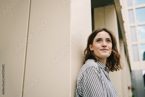 Foto Young Woman Positively Gazing Upwards by Modern Building