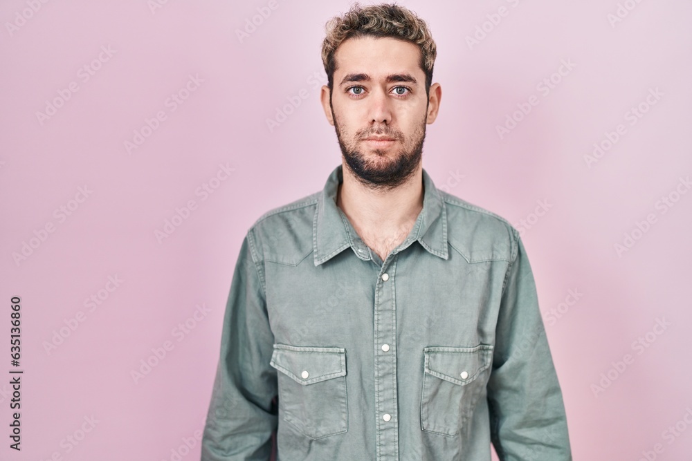 Hispanic man with beard standing over pink background relaxed with serious expression on face. simple and natural looking at the camera. Hispanic man with beard standing over pink background relaxed with serious expression on face. simple and natural looking at the camera.