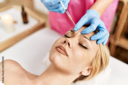 Young caucasian woman lying on table having antiaging treatment at beauty salon