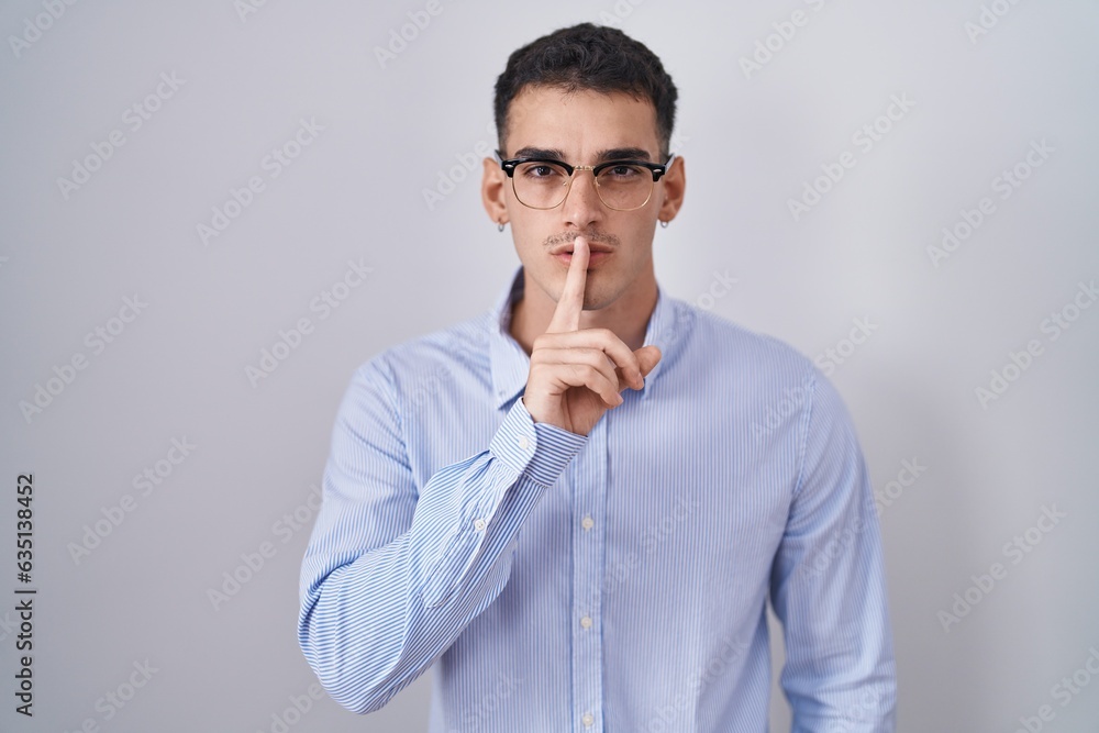 Handsome hispanic man wearing business clothes and glasses asking to be quiet with finger on lips. silence and secret concept. Handsome hispanic man wearing business clothes and glasses asking to be quiet with finger on lips. silence and secret concept.