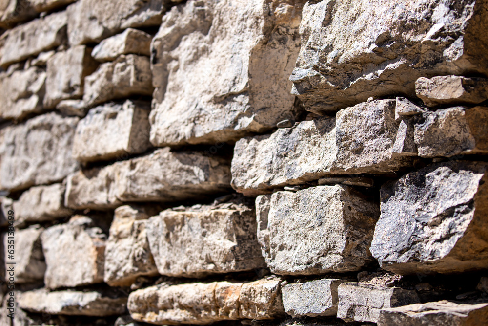 Fototapeta premium Stone antique old wall as a background or texture. Vintage background of a fortress wall in loft and grunge style with place for text and copy space.