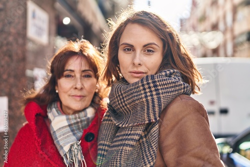 Two women mother and daughter standing together with relaxed expression at street