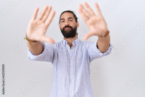 Hispanic man with beard wearing casual shirt doing frame using hands palms and fingers, camera perspective