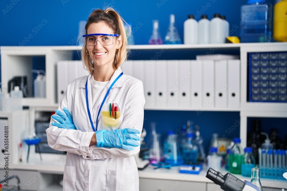 Young woman scientist smiling confident standing with arms crossed gesture at laboratory
