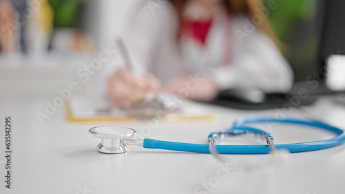 Young hispanic woman doctor writing medical report at clinic