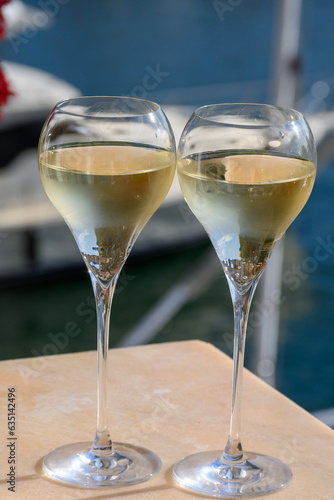 Drinking of French brut champagne sparkling wine in glasses, club party in yacht harbour of Port Grimaud near Saint-Tropez, French Riviera vacation, France