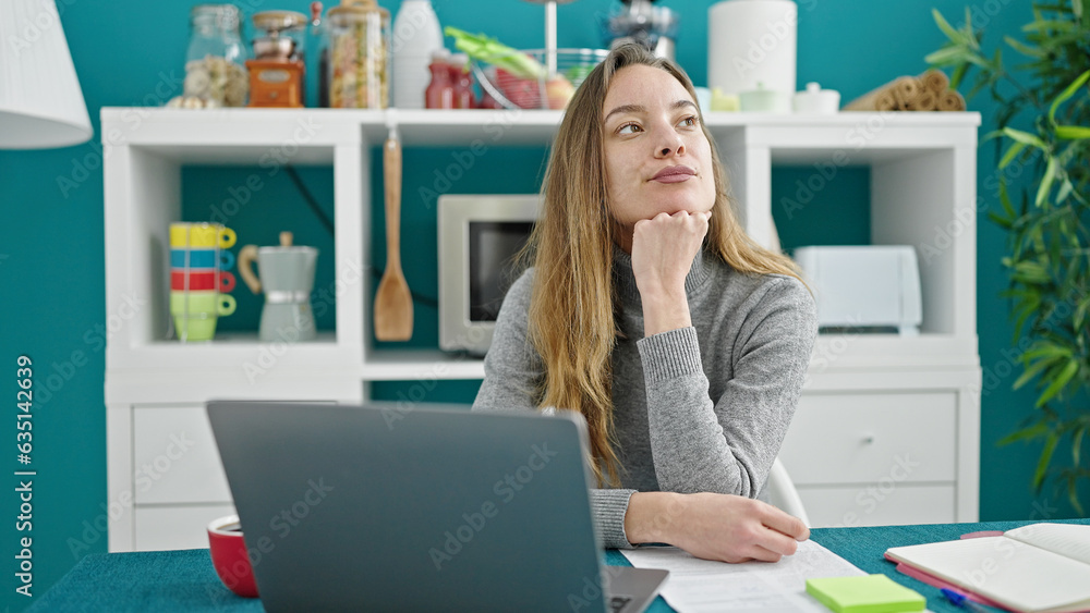 Young caucasian woman using laptop with doubt expression at dinning room Young caucasian woman using laptop with doubt expression at dinning room