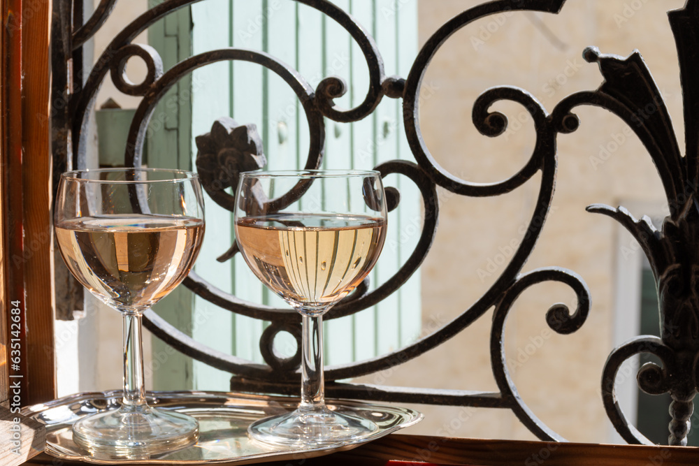 French cold rose dry wine from Provence in glasses served on window frame with wrought iron grille and wooden shutters, Provence, France