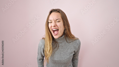 Young caucasian woman screaming over isolated pink background