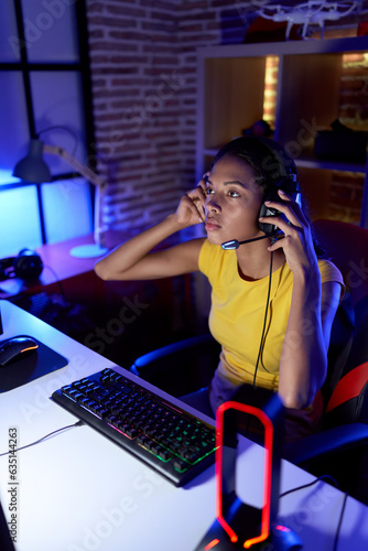 Young african american woman streamer playing video game using computer at gaming room