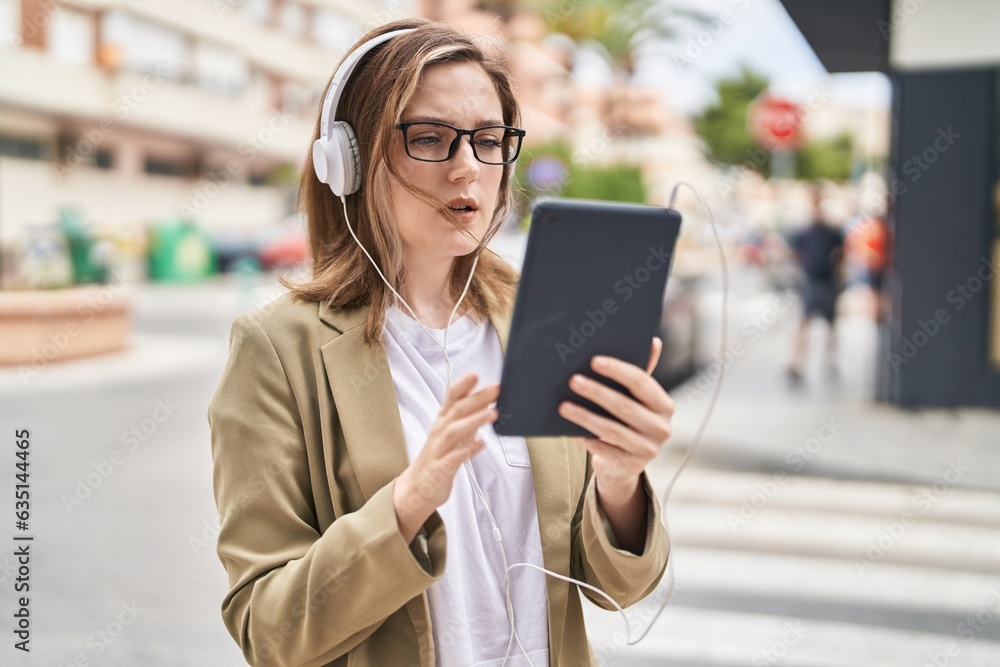 Fototapeta premium Young woman business worker using touchpad and headphones at street