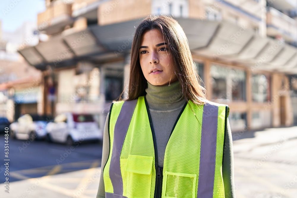 Young beautiful hispanic woman architect standing with serious expression at street