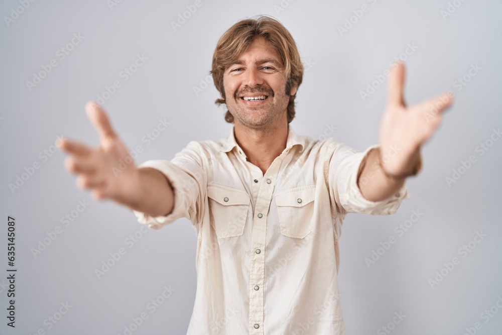 Middle age man standing over isolated background looking at the camera smiling with open arms for hug. cheerful expression embracing happiness. Middle age man standing over isolated background looking at the camera smiling with open arms for hug. cheerful expression embracing happiness.