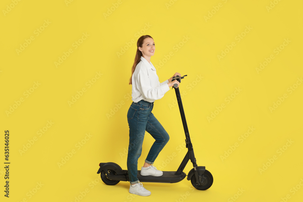 Happy woman with modern electric kick scooter on yellow background Happy woman with modern electric kick scooter on yellow background