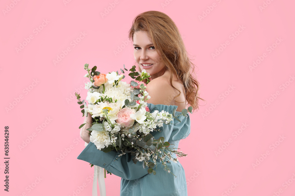 Beautiful woman with bouquet of flowers on pink background