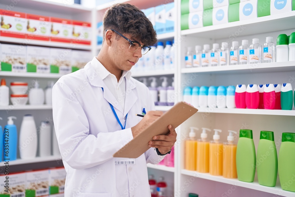 Young hispanic teenager pharmacist writing on document at pharmacy